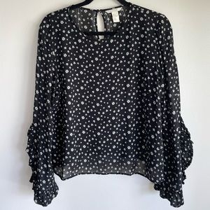 Long sleeved sheer floral top with slit sleeves that have a ruffle edge.